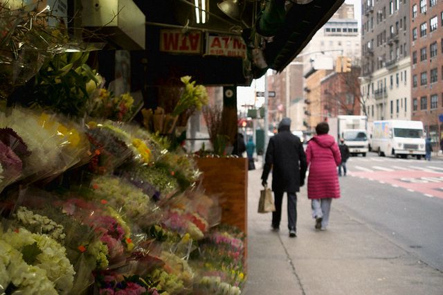 two people walk past a flower stand on the Upper East Side